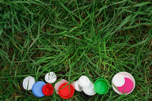 Colorful plastic bottle caps on the green grass. Volunteer charity event \