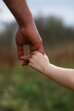 Babasının büyük avucunda küçük bir çocuk eli. Kızım, babamın elini tutuyor. Güçlü bir aile, ebeveynlik, bakım ve yetiştirme. Aile kavramı, koruma, güvenilirlik, parlak bir gelecek.