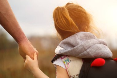Babasının büyük avucunda küçük bir çocuk eli. Kızım, babamın elini tutuyor. Güçlü bir aile, ebeveynlik, bakım ve yetiştirme. Aile kavramı, koruma, güvenilirlik, parlak bir gelecek.
