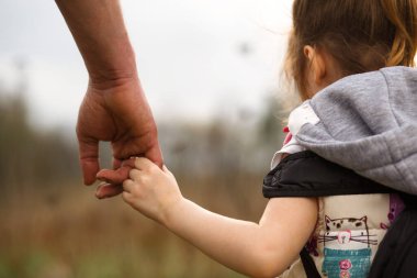 Babasının büyük avucunda küçük bir çocuk eli. Kızım, babamın elini tutuyor. Güçlü bir aile, ebeveynlik, bakım ve yetiştirme. Aile kavramı, koruma, güvenilirlik, parlak bir gelecek.