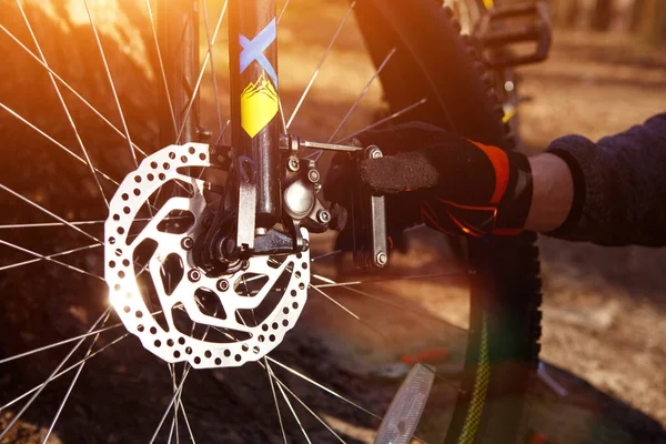 自転車の車輪とブレーキの近くにマルチツールを持つ男の手 自転車の修理 ディスクブレーキとスピードスイッチを設定し 道路の修理キットは 乗車の準備 — ストック写真