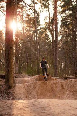 Kaluga, Rusya-9 Nisan 2020. Ormandaki bisikletçiler, dağ bisikleti sporu için slaytlarla bir pistte. Dağ bisikleti atlama, ekstrem sporlar.