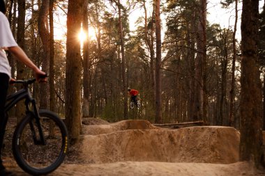 Kaluga, Rusya-9 Nisan 2020. Ormandaki bisikletçiler, dağ bisikleti sporu için slaytlarla bir pistte. Dağ bisikleti atlama, ekstrem sporlar.