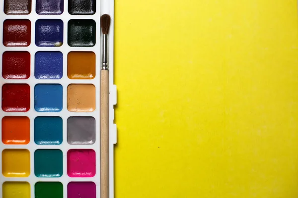 Een Palet Van Achttien Kleuren Aquarellen Penselen Een Gele Achtergrond — Stockfoto