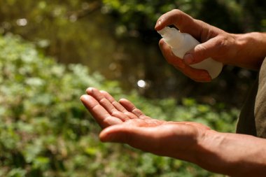 Bir adam kirli ellere antiseptik sıkar. Sağlık, temizlik, tehlikeli bakteri ve virüslerden korunma. Koronavirüs salgınının yayılması sırasında hijyen, sokaklarda ve doğada
