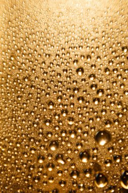 Parlak altın bir arka planda bulanık bir su damlasının dokusu. Makro damlaların arkaplanı