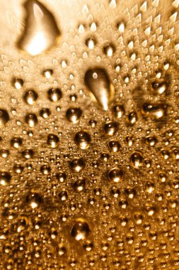Parlak altın bir arka planda bulanık bir su damlasının dokusu. Makro damlaların arkaplanı