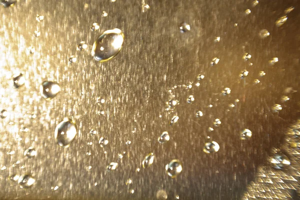 Texture of a water drop on a shiny gold background in a blur. Background of macro drops