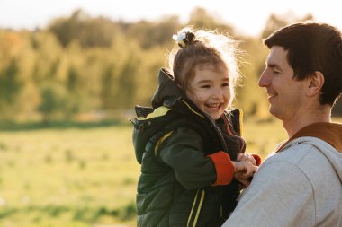 Babasının kollarında mutlu ve gülen, babasıyla oynayan küçük bir kız. Babalar günü, yaşam tarzı, çocukların duyguları, aile ilişkileri. Metin için boşluk