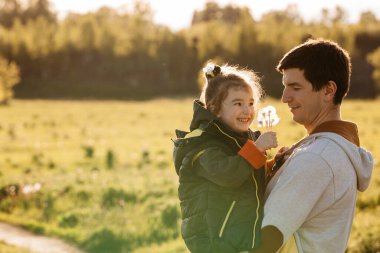 Küçük bir kız babasına çiçek beyazı karahindiba verir, baba kızını kollarına alır. Babalar günü, mutlu çocuk duyguları, yaşam tarzı, mesajlaşma yeri.