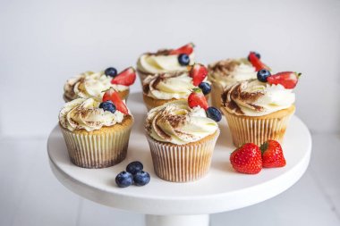 Pasta krema, kakao ile silkeledi ve süslenmiş Beyaz ahşap masa üzerinde bir yaban mersini ve çilek ile.