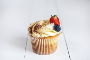 Pasta krema, kakao ile silkeledi ve süslenmiş Beyaz ahşap masa üzerinde bir yaban mersini ve çilek ile.