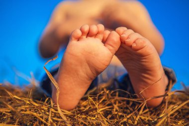 Bacaklar alan samanlıkta oturan küçük bir çocuk