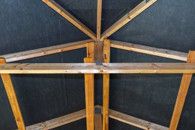 Çatı kirişleri yapım aşamasındaki müstakil bir evin zarı, içeriden görüş, görünür çatı unsurları ve kiriş plakaları ile kaplıdır..