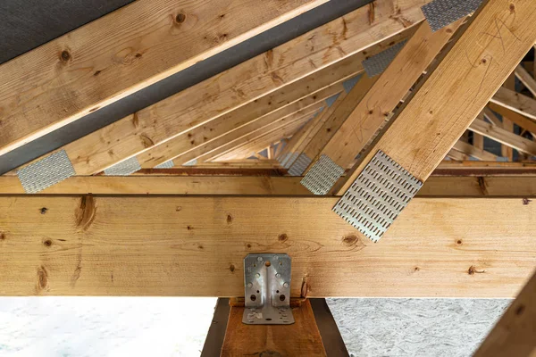 Roof trusses covered with a membrane on a detached house under construction, view from the inside, visible roof elements and truss plates.