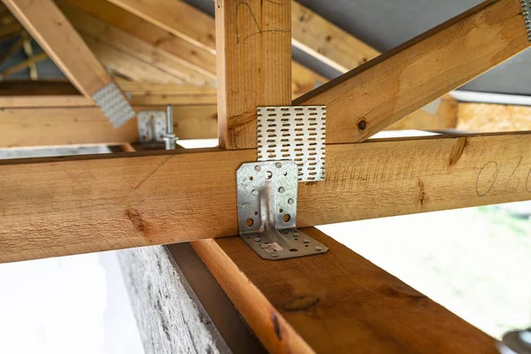 Roof trusses covered with a membrane on a detached house under construction, view from the inside, visible roof elements and truss plates.