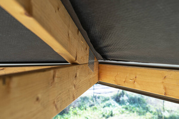 Roof trusses covered with a membrane on a detached house under construction, view from the inside, visible roof elements and truss plates.