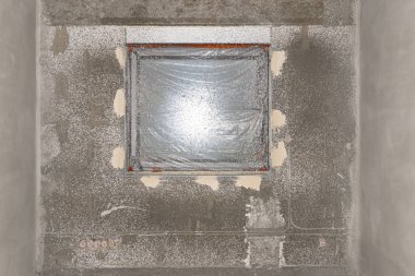 Yapılan evdeki pencereler, çimento kireç alçısının uygulanması sırasında folyoyla korunuyor..