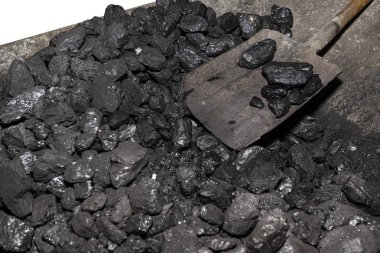 Küreğin yattığı kömür dolu el arabası, kesme yolu olan beyaz bir arka planda izole edilmiş..