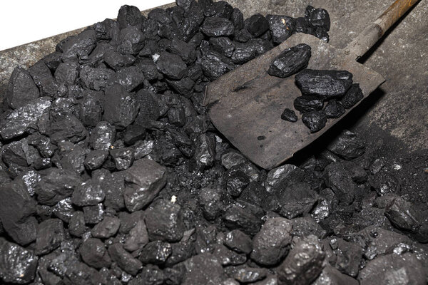 Wheelbarrow loaded with coal on which the shovel lies, isolated on a white background with a clipping path.