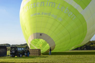 Wershofen, Almanya 3 Eylül 2017. Havayı gaz ocağıyla ısıtarak yeşil bir sıcak hava balonunu uçuşa hazırlıyorum. Balon kalkış tahtasının üzerinde duruyor..