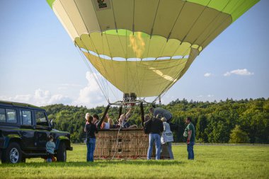 Wershofen, Almanya 3 Eylül 2017. Yeşil bir sıcak hava balonu fırlatıyorlar, insanlar gondolda duruyorlar. Balon yerde..