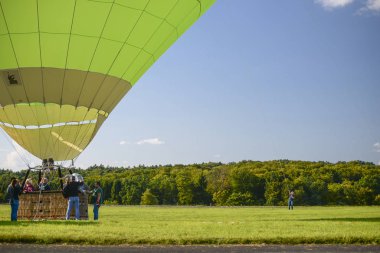 Wershofen, Almanya 3 Eylül 2017. Yeşil bir sıcak hava balonu fırlatıyorlar, insanlar gondolda duruyorlar. Balon yerde..
