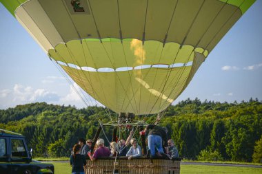 Wershofen, Almanya 3 Eylül 2017. Yeşil bir sıcak hava balonu fırlatıyorlar, insanlar gondolda duruyorlar. Balon yerde..