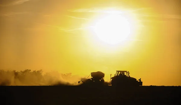 Bir Traktörün Silueti Batan Güneşin Arka Planına Karşı Bir Toz — Stok fotoğraf