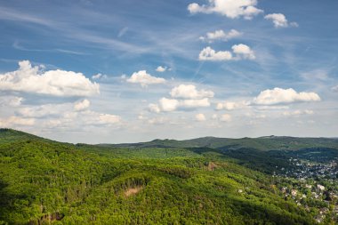 Landscape of green forest on the hills in summer with blue sky and white clouds. Photo taken in West Germany.