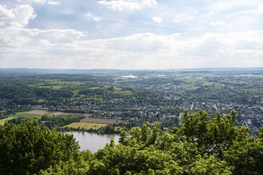 Batı Almanya 'da Rhein Nehri bulutlarla gökyüzüne karşı şehir boyunca akar. Nehirde görünür mavnalar ve gemiler.