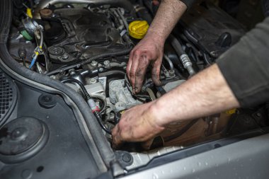 Tamirci yakıt borusundaki pompayla yakıt sistemini kanatıyor. Yeni bir yakıt filtresi taktıktan sonra insan eli görünür hale geliyor..