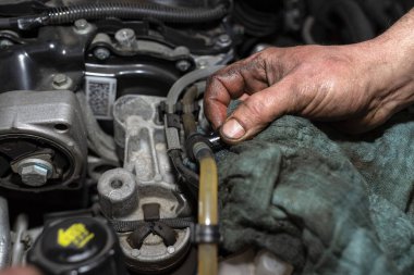 Tamirci yakıt borusundaki pompayla yakıt sistemini kanatıyor. Yeni bir yakıt filtresi taktıktan sonra insan eli görünür hale geliyor..