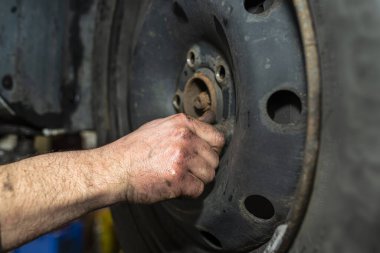 Araba tamircisi, pnömatik anahtarı kullanmadan önce sürgüleri yerleştirir ve arabanın çelik tekerleğini emniyete alır..