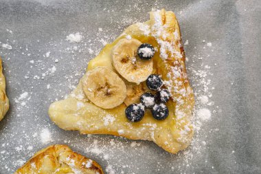 Puding, muz ve yaban mersinli pudra şekerli pudra kağıdına serpiştirilmiş pudra şekerli poğaçalardan yapılan kurabiyeler..