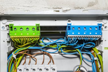 Elektrik kabloları için yeşil-sarı ve mavi kenetleme bloğu, elektrik kutusuna bağlı kablolarla bağlanmış..