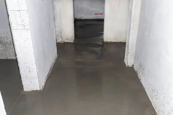 Watering a newly poured floor screed at home to prevent it from cracking.