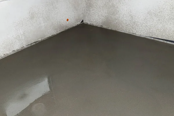 Watering a newly poured floor screed at home to prevent it from cracking.