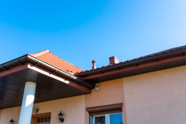 Binanın yüksekliği somon renginde beton sütun, ahşap sabun ve duvarda güvenlik kameraları var..