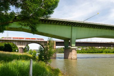 Batı Almanya 'da mavi gökyüzü arka planına sahip bir nehir üzerinde çelik bir karayolu köprüsü ve beton bir demiryolu köprüsü..