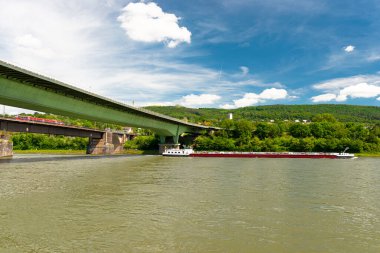 Batı Almanya 'da mavi gökyüzü arka planına sahip bir nehir üzerinde çelik bir karayolu köprüsü ve beton bir demiryolu köprüsü..