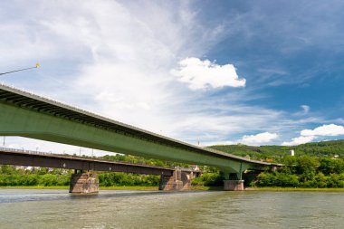 Batı Almanya 'da mavi gökyüzü arka planına sahip bir nehir üzerinde çelik bir karayolu köprüsü ve beton bir demiryolu köprüsü..