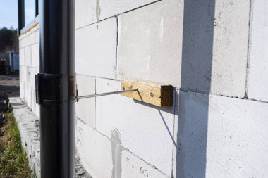 Binayı izole etmek için evin ham duvarına bağlanmış siyah metal bir oluk..