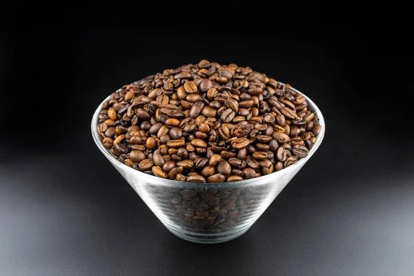 Taze Kavrulmuş Kahve Çekirdekleri Cam Bir Kasede Siyah Bir Masanın — Stok fotoğraf