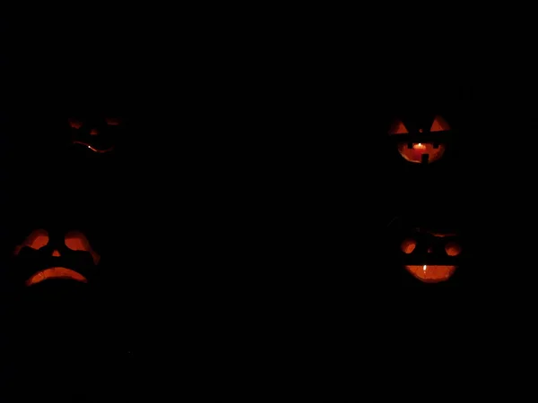 Gruselige Halloween-Kürbisse isoliert auf schwarzem Hintergrund. Glühende Gesichter tricksen oder behandeln — Stockfoto