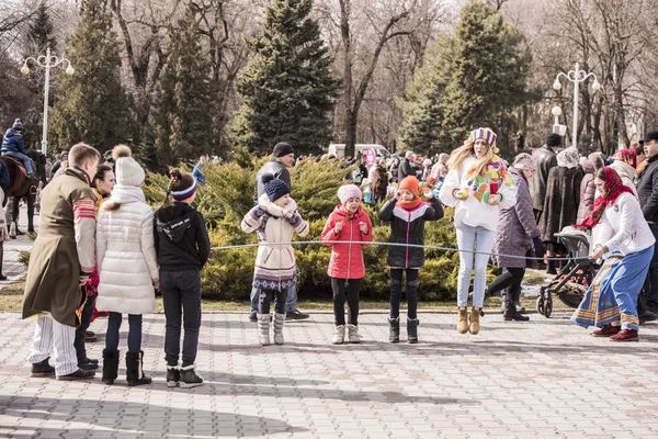 Maslenitsa- Mädchen springen durch einen Pullover im Park bei carni — Stockfoto