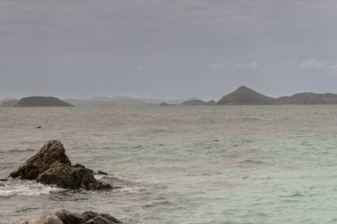 Ko Kham adasında kayalık bir sahil ve sörf. Tayland