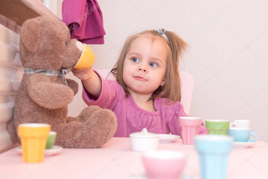 2 years old girl playing tea party with a teddy bear