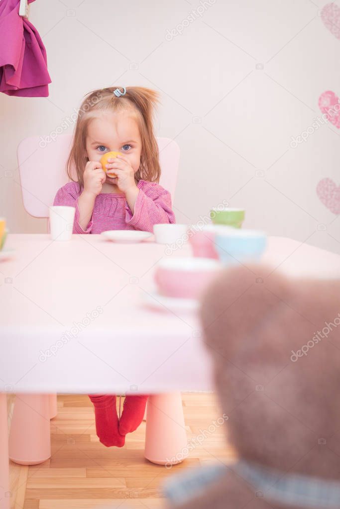 2 years old girl playing tea party with a teddy bear