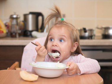 1,5 years old girl eating by herself clipart
